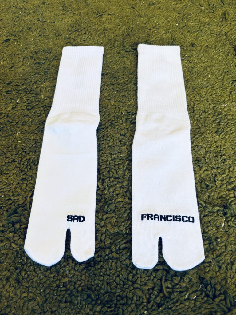 Sad Francisco tabi socks. White with black lettering.